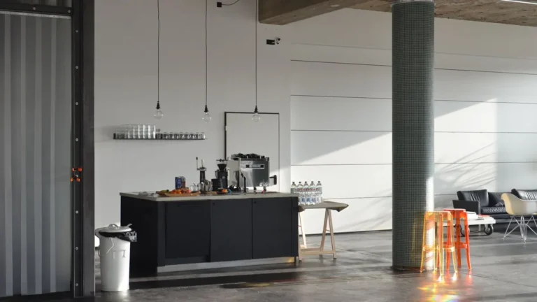 Ruime loft met donkergrijze naadloze vloer, betonnen kolom en open keuken