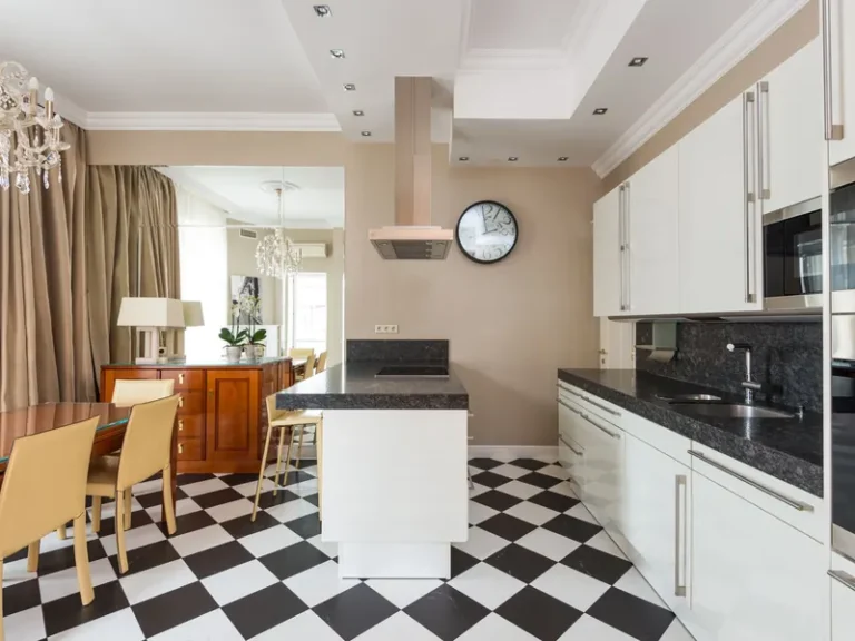 Keuken met een zwart-wit geblokte vloer, kookeiland en eettafel