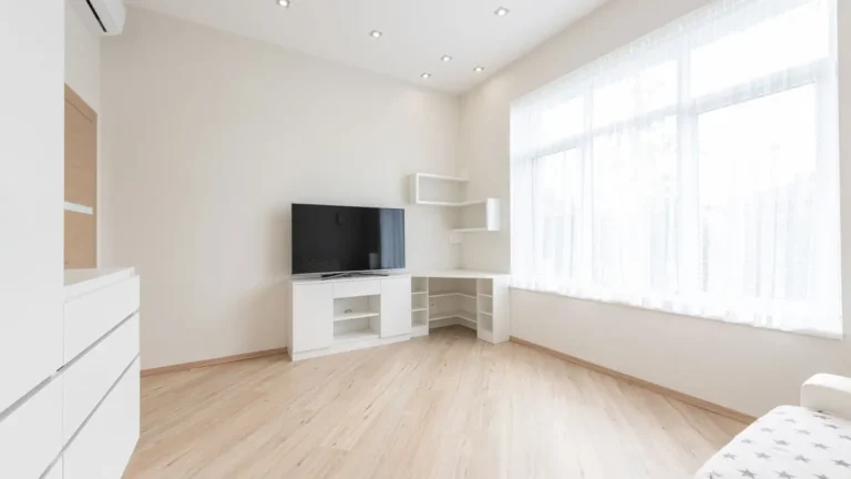 Lichte, lege kamer met een nieuw gelegde lichte laminaatvloer en grote ramen