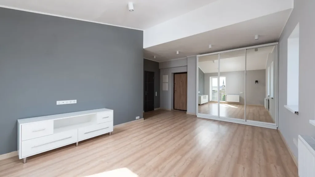 Moderne lichte kamer met een vloer van lichte planken met houtlook en een wit tv-meubel