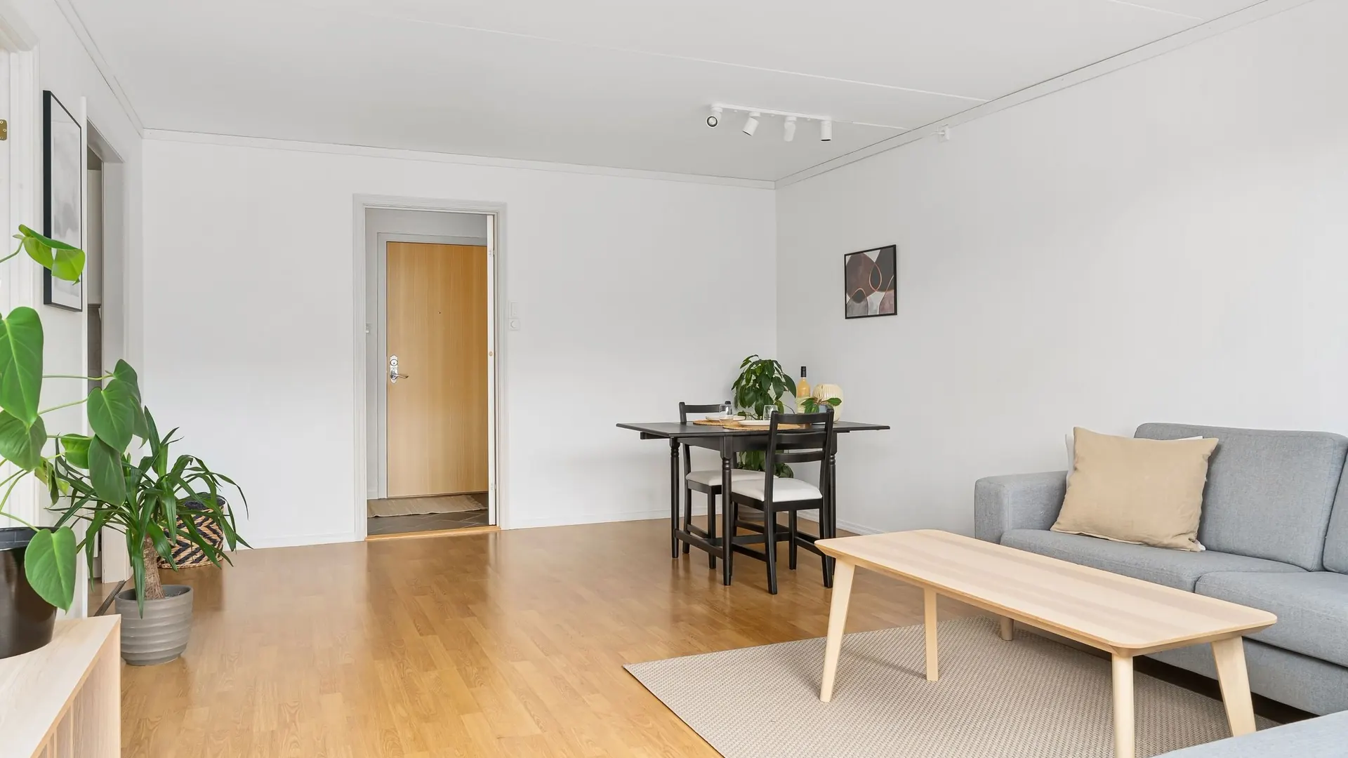 Lichte woonkamer met een eikenhouten plankenvloer, grijze bank en houten salontafel