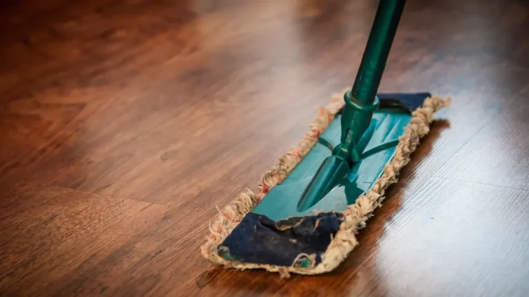 Stofwisser met microvezelmop op een glanzende bruine houten vloer