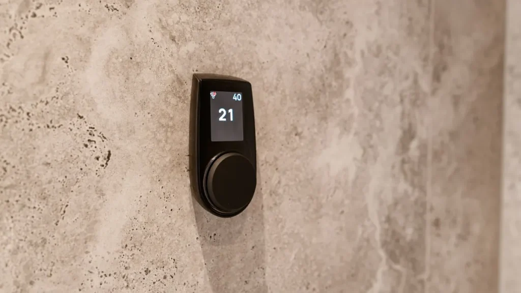 Digitale thermostaat op een wand van natuursteen die 21 graden aangeeft