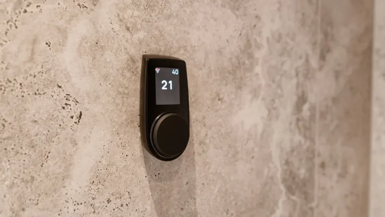 Digitale thermostaat op een wand van natuursteen die 21 graden aangeeft
